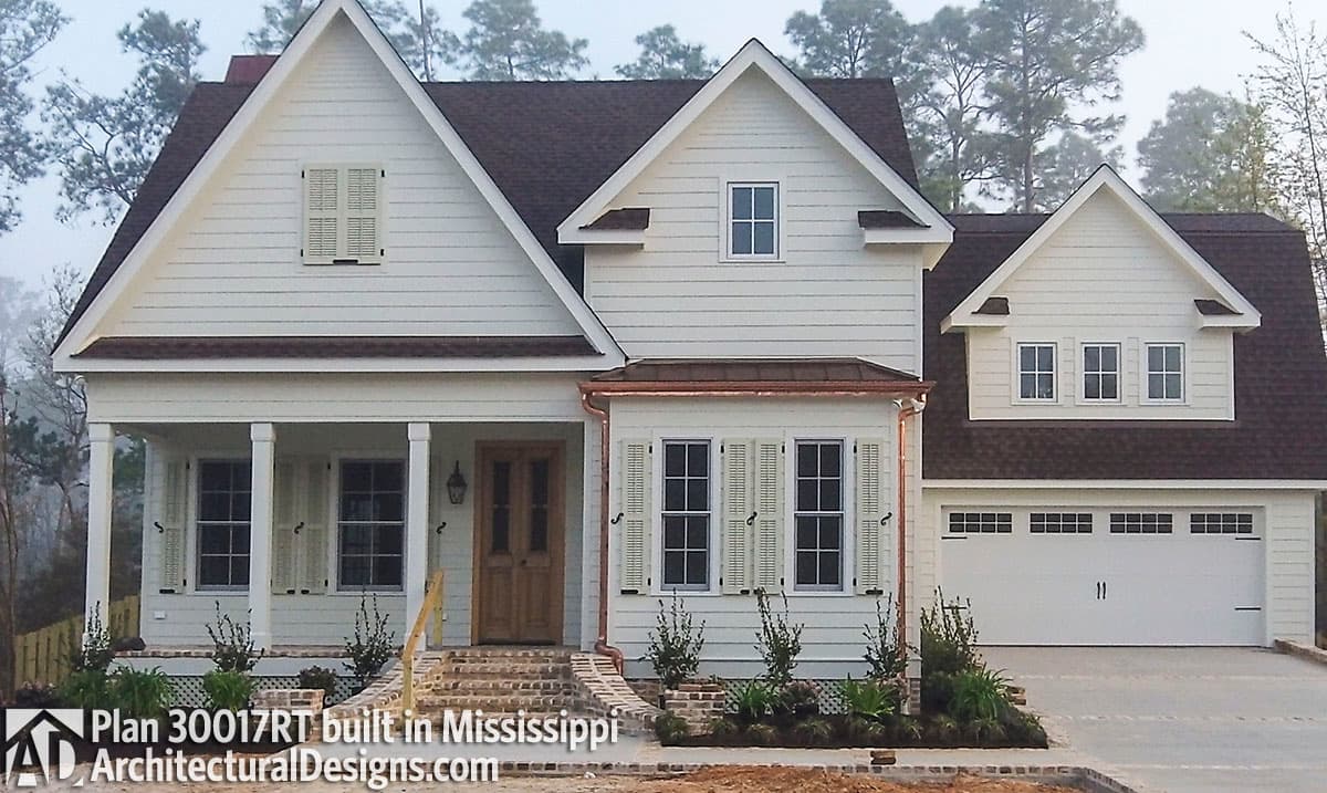 House plan exterior: Two-story Modern Farmhouse with a gabled roof, covered front porch, and attached side-entry garage.