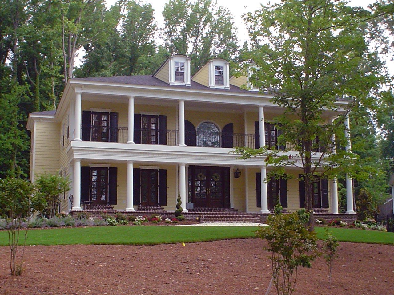 Colonial style house plan exterior with a two-story full-width covered porch supported by Doric columns and dormer windows.