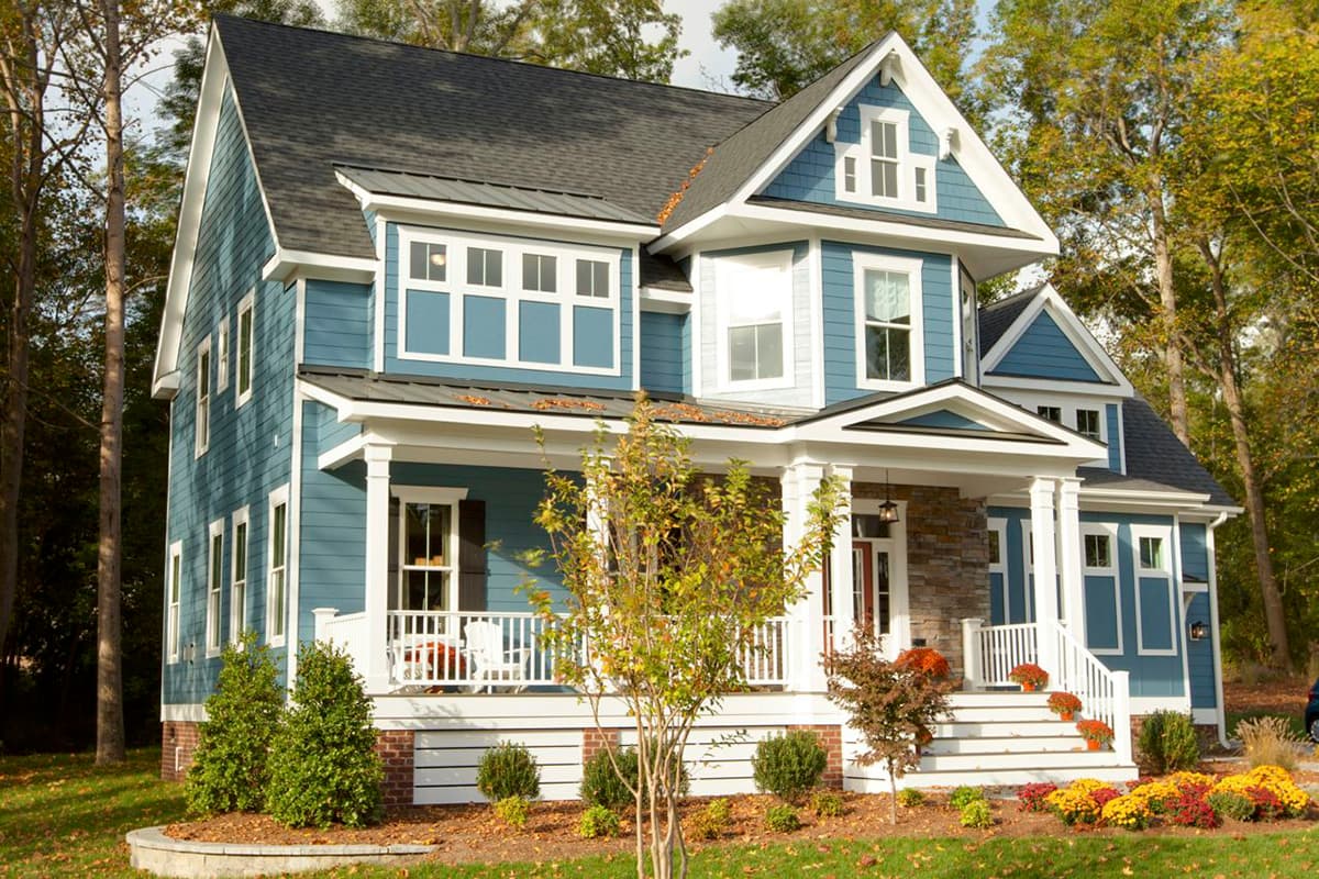 House plan exterior for a two-story home with a gabled roof, wraparound porch, and stone accents.
