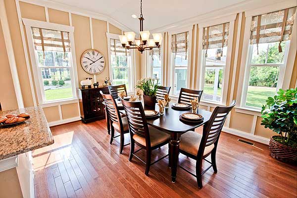 Dining room with dark wood table and chairs, wainscoting, and multiple windows providing natural light.