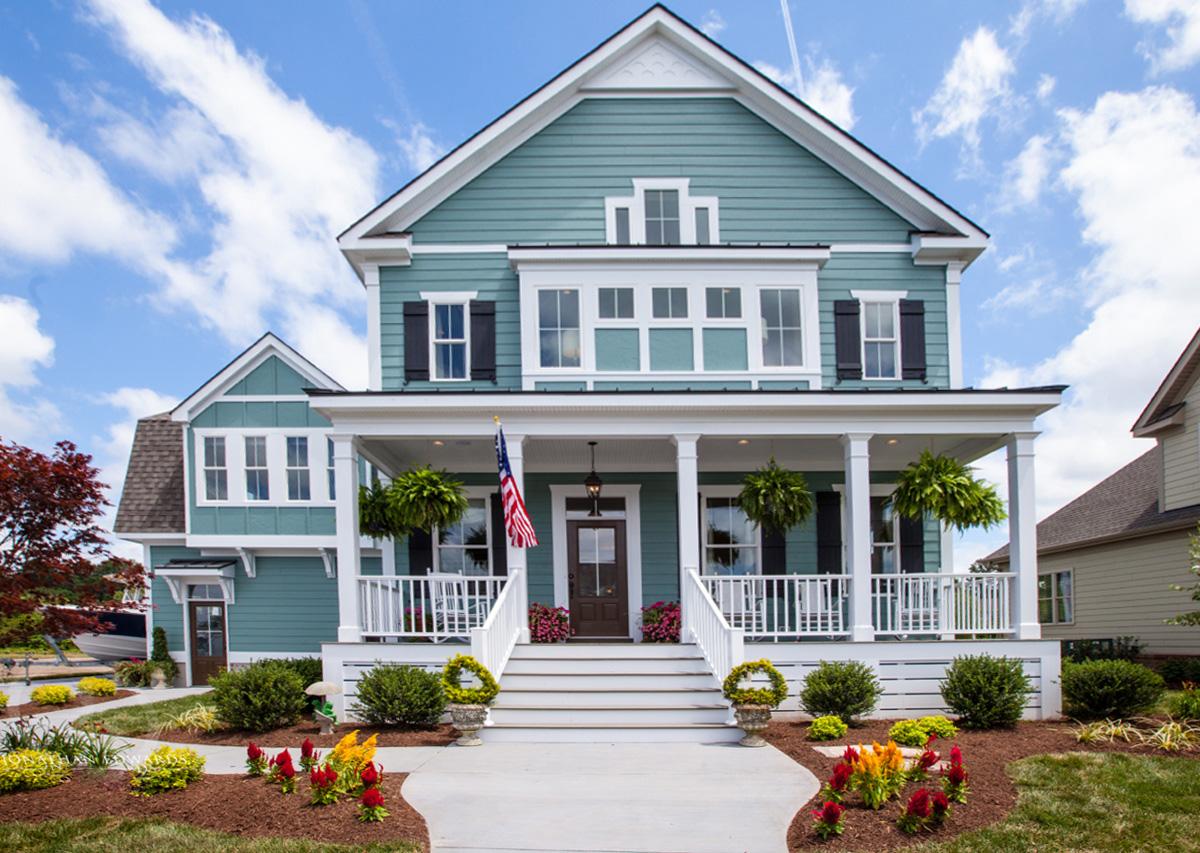 House plan exterior: Two-story home with wraparound porch, dormer windows, and gabled rooflines.