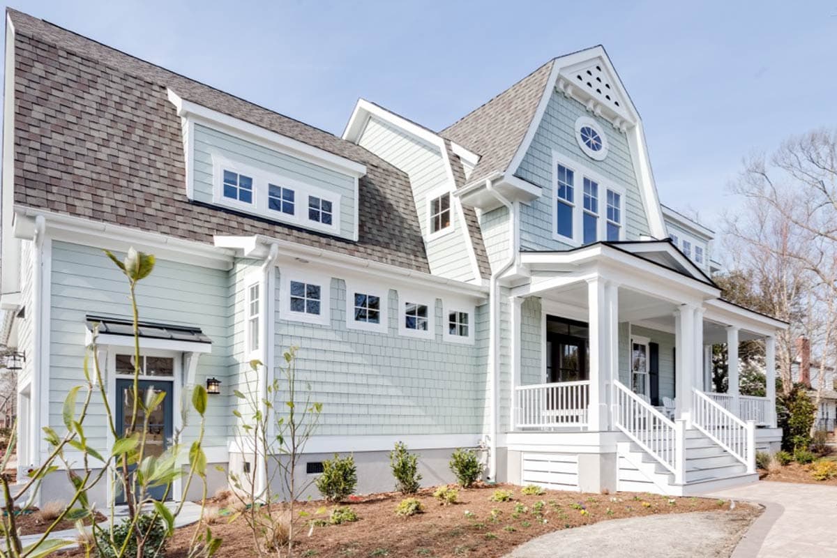 House plan exterior featuring a wraparound porch, multiple gables, dormer windows, and cedar shake siding.