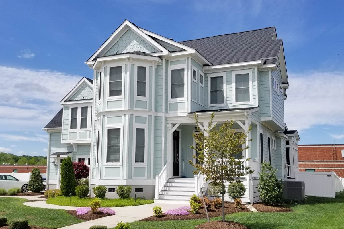 House plan exterior: Traditional style, two stories, with bay windows, gabled dormers, and a covered front porch.