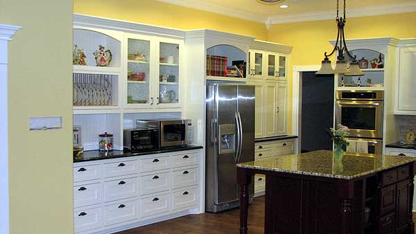 Kitchen interior featuring white cabinetry, stainless steel appliances, granite island, and a built-in oven.
