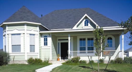 House plan exterior with a prominent bay window, arched windows, and a wraparound porch with white railing.