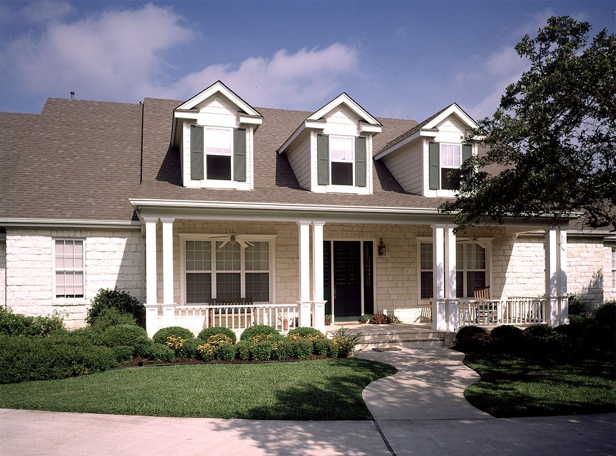 House plan exterior with stone facade, covered front porch, three dormers, and a gabled roof.