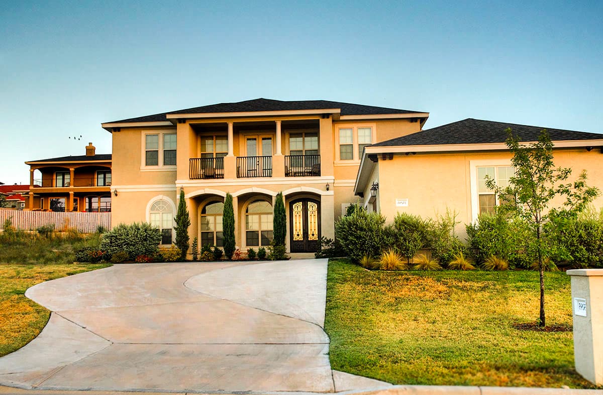 House plan exterior: two-story Mediterranean style with arched windows, double doors, upper balconies, and stucco finish.