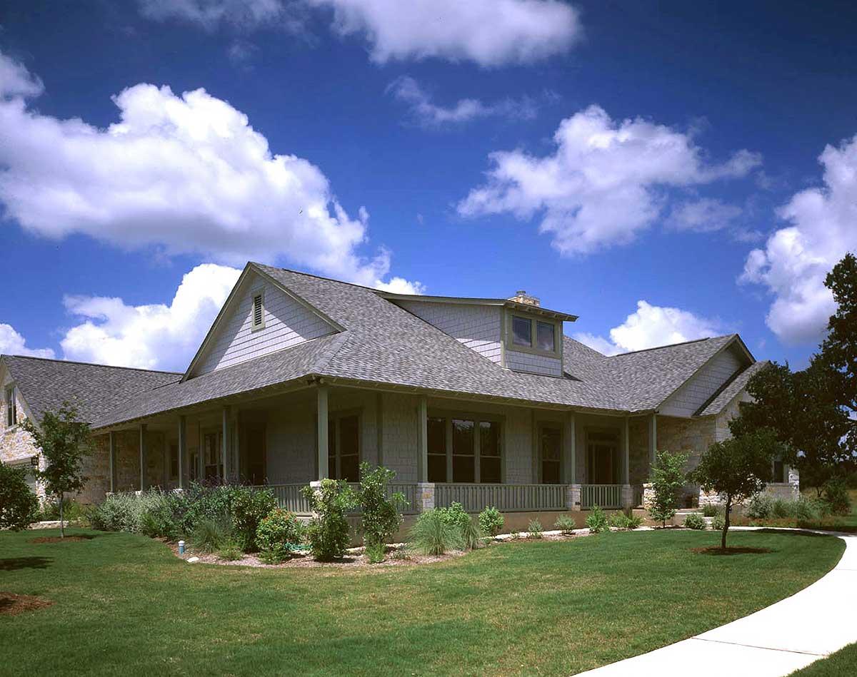 House plan exterior: Ranch style, one story, with a wrap-around porch, gable dormer, and stone accents.