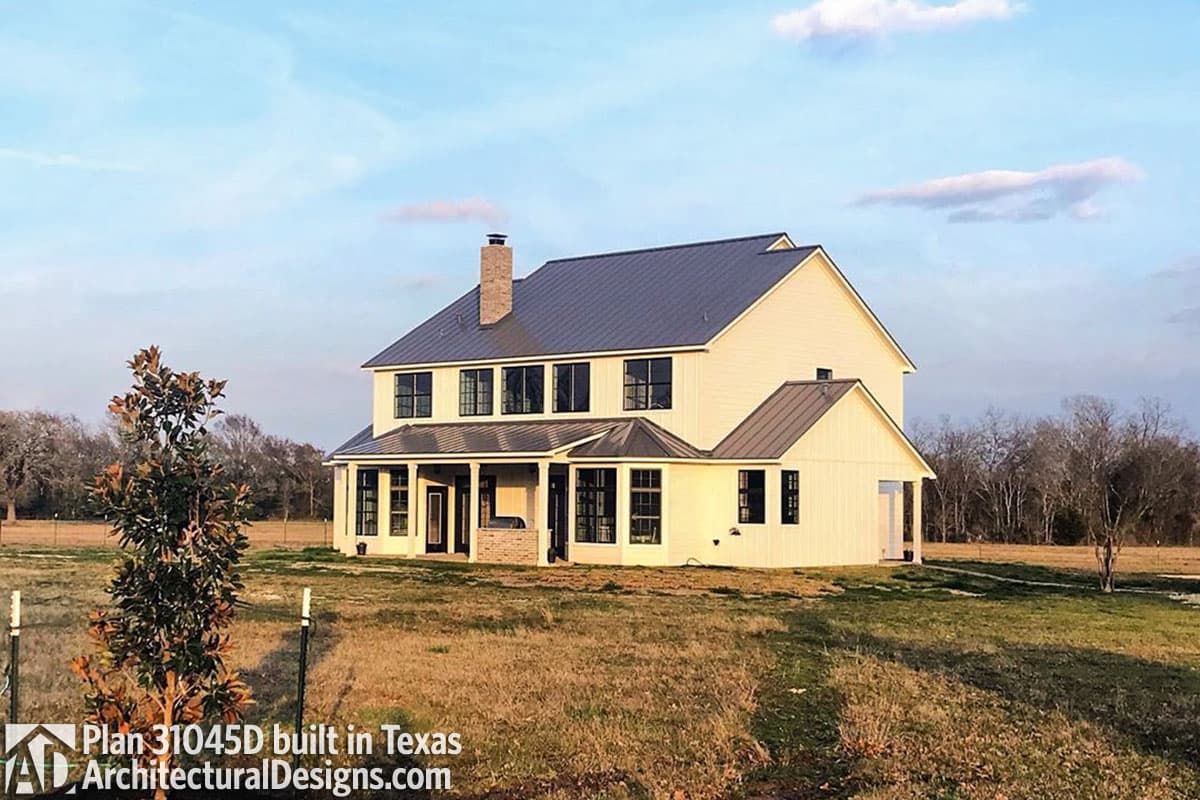 House plan exterior: Two-story Modern Farmhouse with metal roof, gabled dormers, and covered front porch with brick accents.