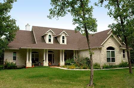 House plan exterior: single-story home with stone facade, wraparound porch, and two front dormers.