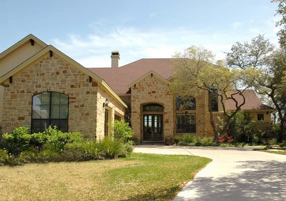 House plan exterior with stone facade, prominent gables, arched entryway, and multiple stories.