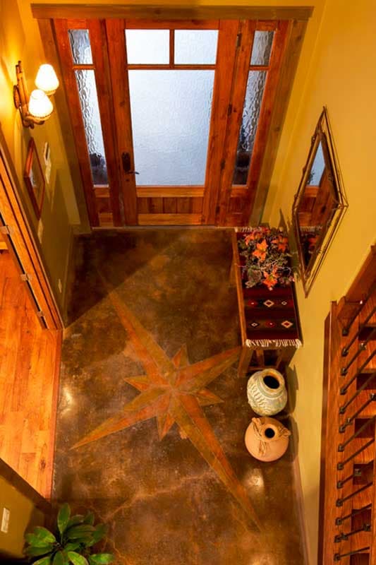Entryway interior with double wood doors, frosted glass panes, a compass rose stained concrete floor, and decorative vases.