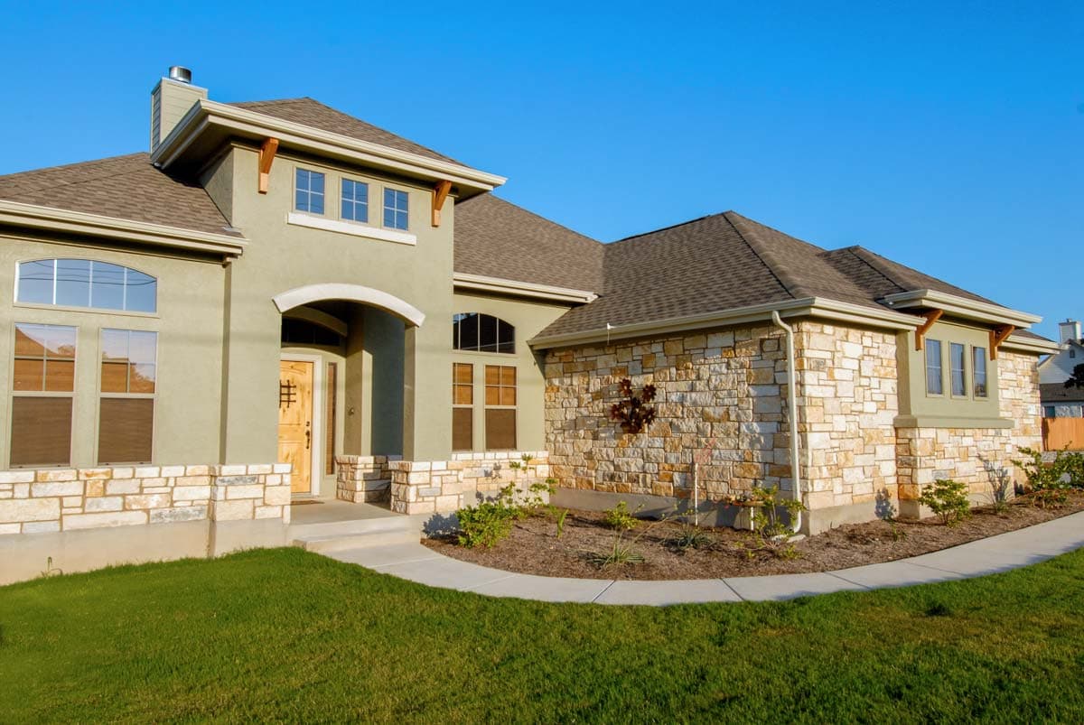 House plan exterior: One-story home with arched entry, stone accents, and gabled rooflines.