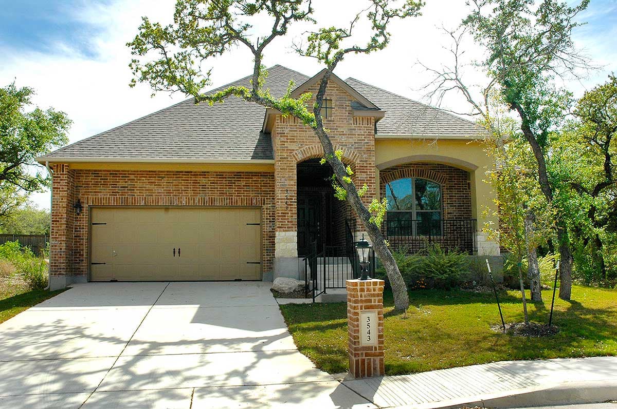 House plan exterior: Single-story home with brick and stucco facade, arched entryway, and attached garage.