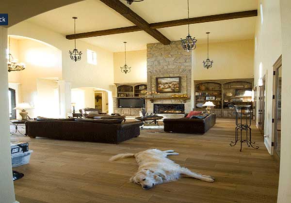 Great room with vaulted ceiling, exposed beams, stone fireplace, built-in shelving, and hardwood floors.