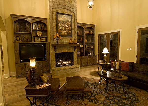 Living room interior with stone fireplace, built-in cabinetry, and hardwood floors.