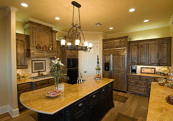 Kitchen with dark wood cabinets, granite countertops, island with sink, and stainless steel refrigerator.