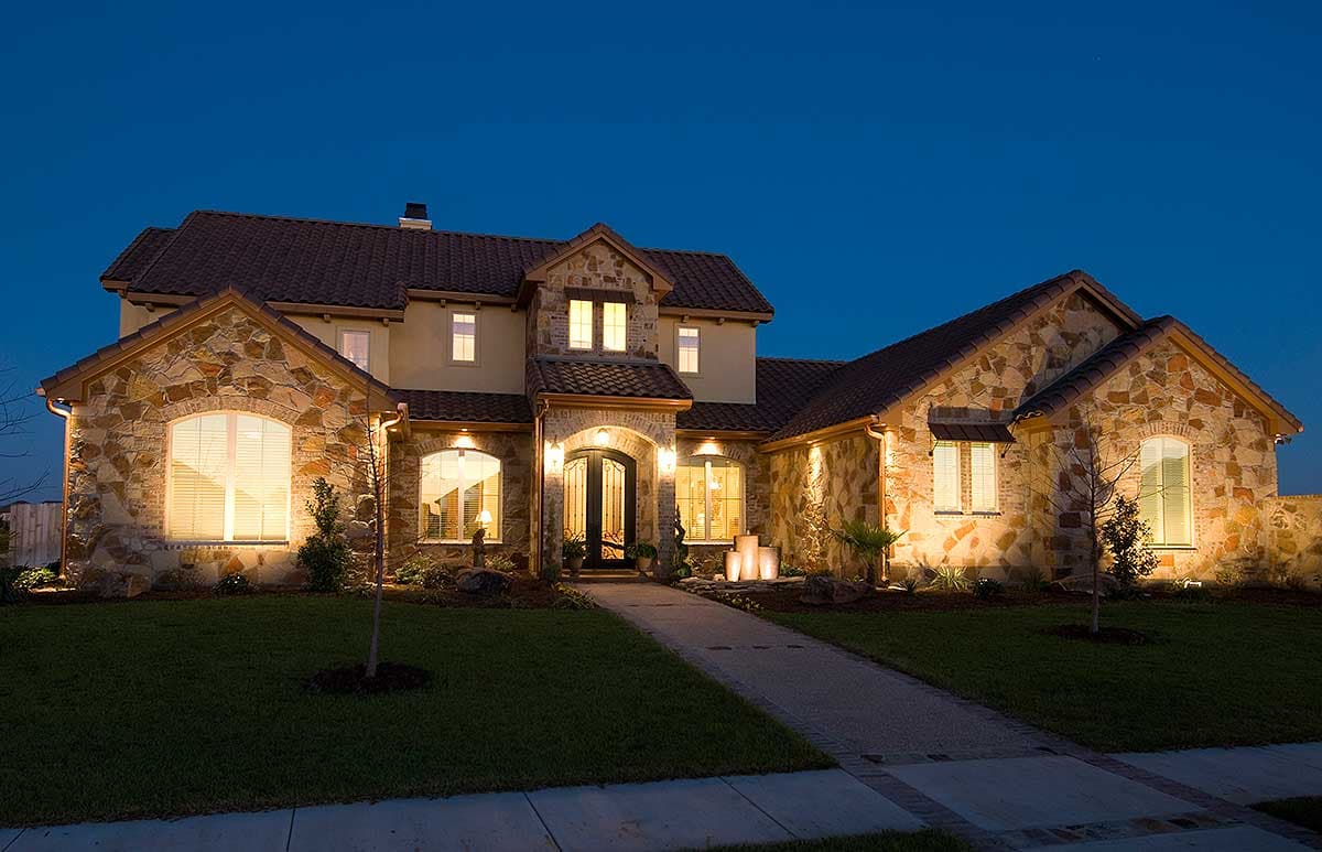 House plan exterior of a two-story home with stone facade, arched windows, double entry doors, and a tile roof.