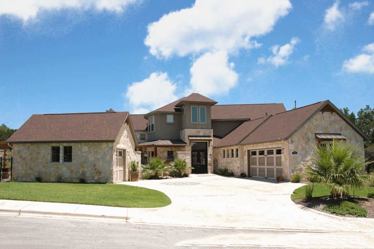 House plan exterior featuring stone veneer, multi-story design, gabled roofs, and a porte-cochère.