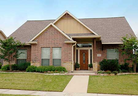 House plan exterior: One-story brick home with prominent gable, covered entry with wood door, and double front windows.