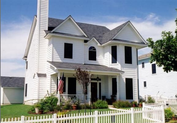 House plan exterior: two-story white home with prominent chimney, gables, covered front porch, and arched window above entrance.