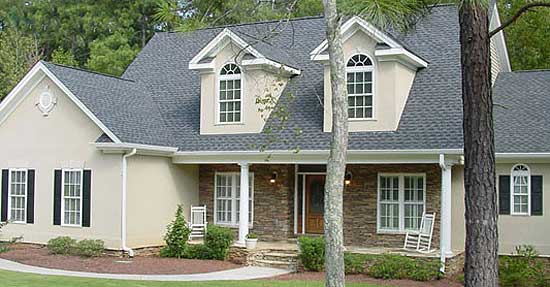 House plan exterior: two-story dwelling with arched dormer windows, covered porch with stone accent, and stucco siding.