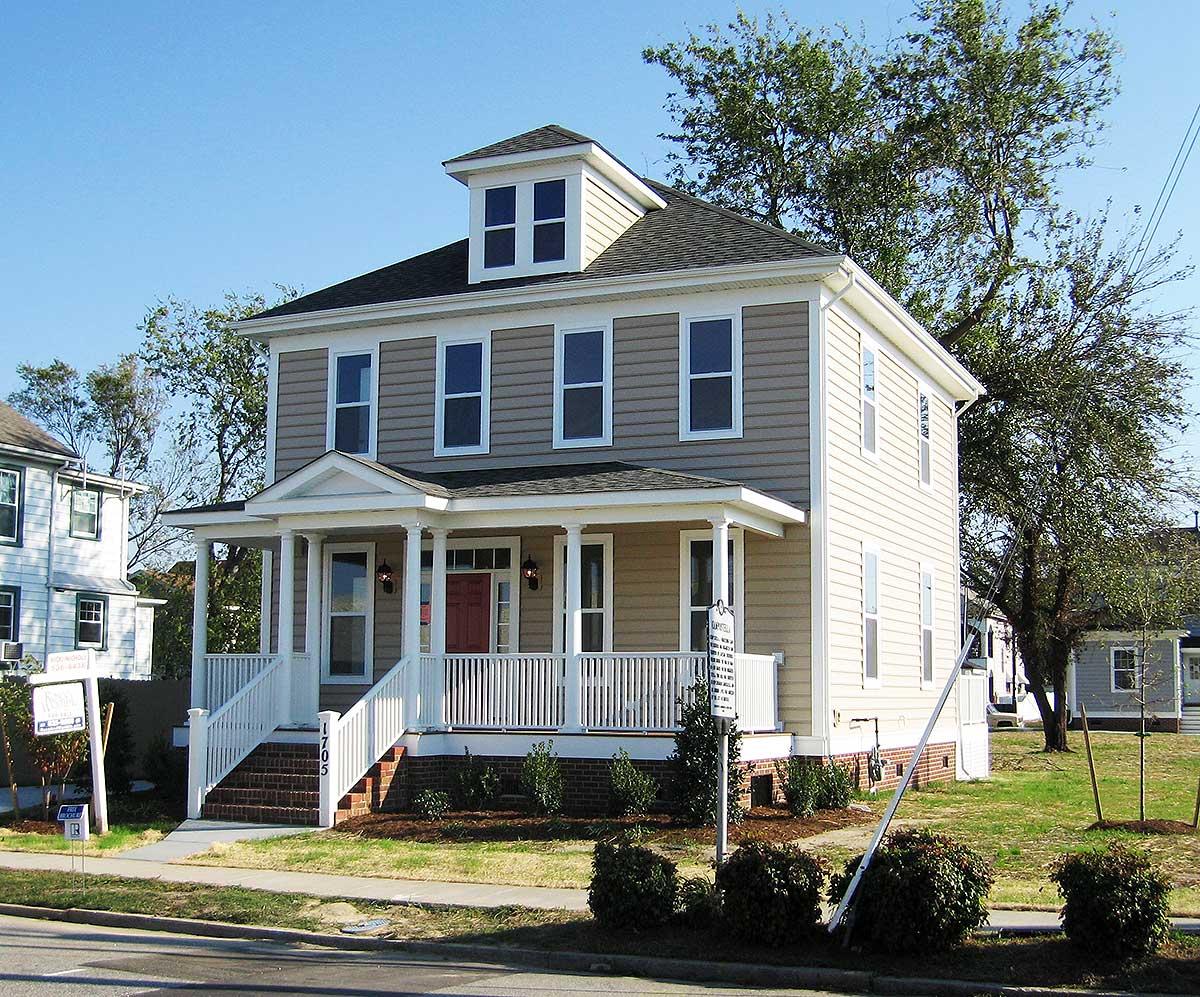 Traditional two-story house plan exterior with wrap-around porch, dormer, and prominent gables.