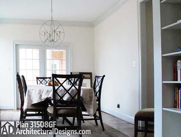 Dining room with table, chairs, double doors, and built-in bookshelf. Plan 31508GF.