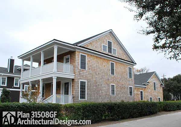 House plan exterior: Two-story building with cedar shingles, a wraparound porch with white railings, and dormer windows.