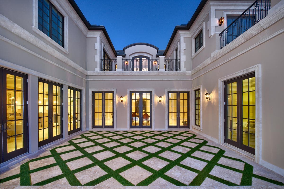Exterior house plan with symmetrical courtyards, French doors, balconies, and patterned turf paving.