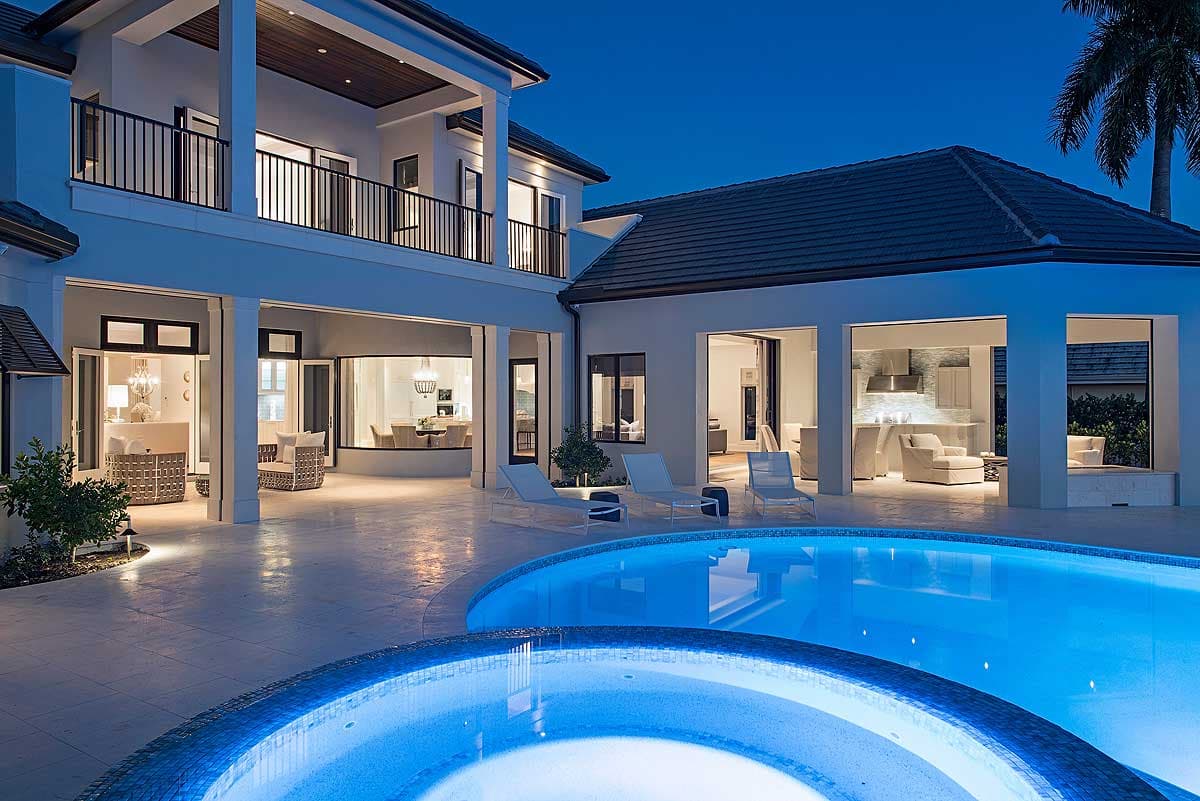 House plan exterior: two-story modern design with balconies, covered patios, open-concept interior views, and a curvilinear pool.