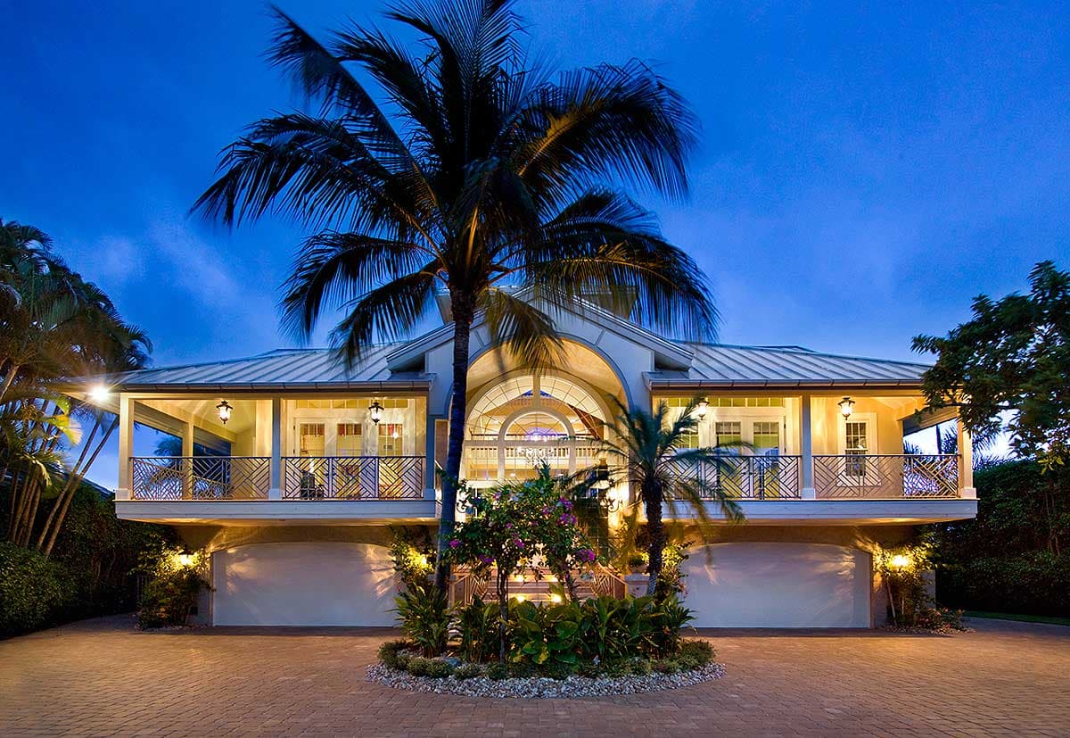 House plan exterior with a raised foundation, wraparound porch, metal roof, and three garage bays.