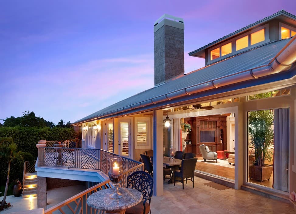 House plan exterior with multi-level patio, stone chimney, and wide eaves. Interior visible.