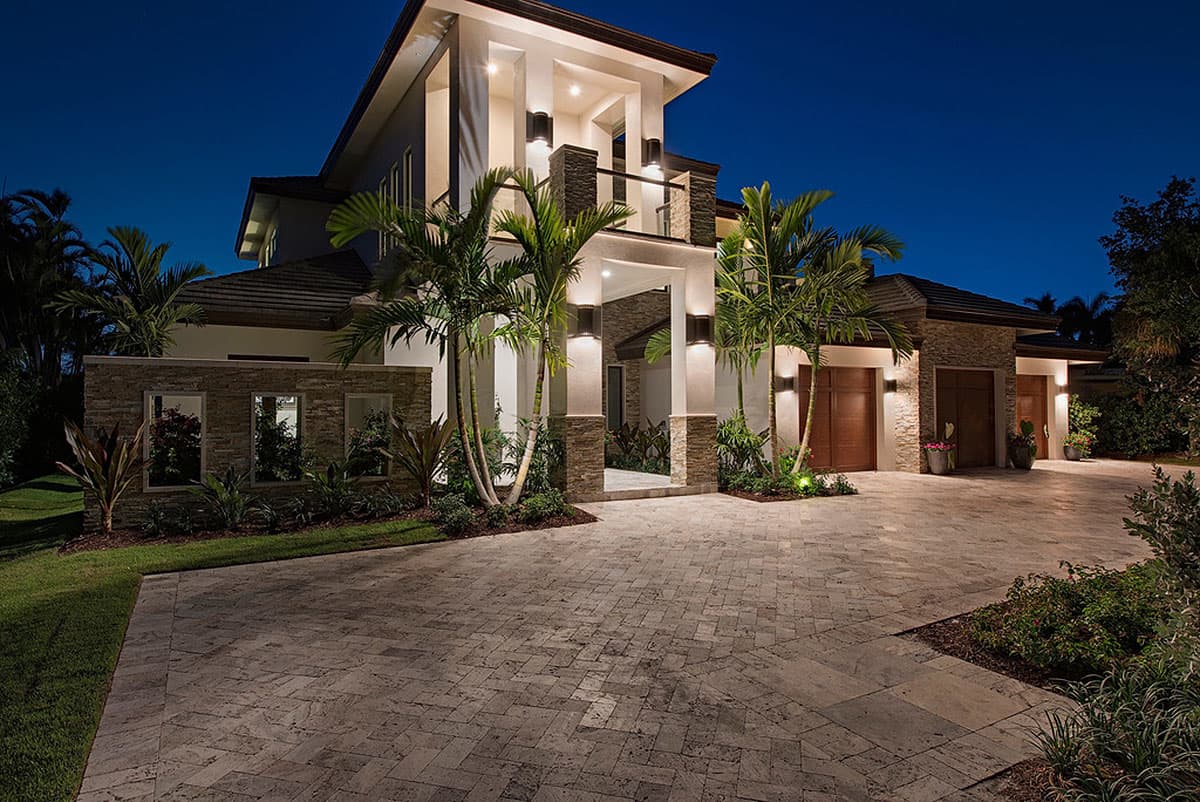 Modern two-story house plan exterior with stone accents, multiple garage doors, a covered entrance, and balcony.