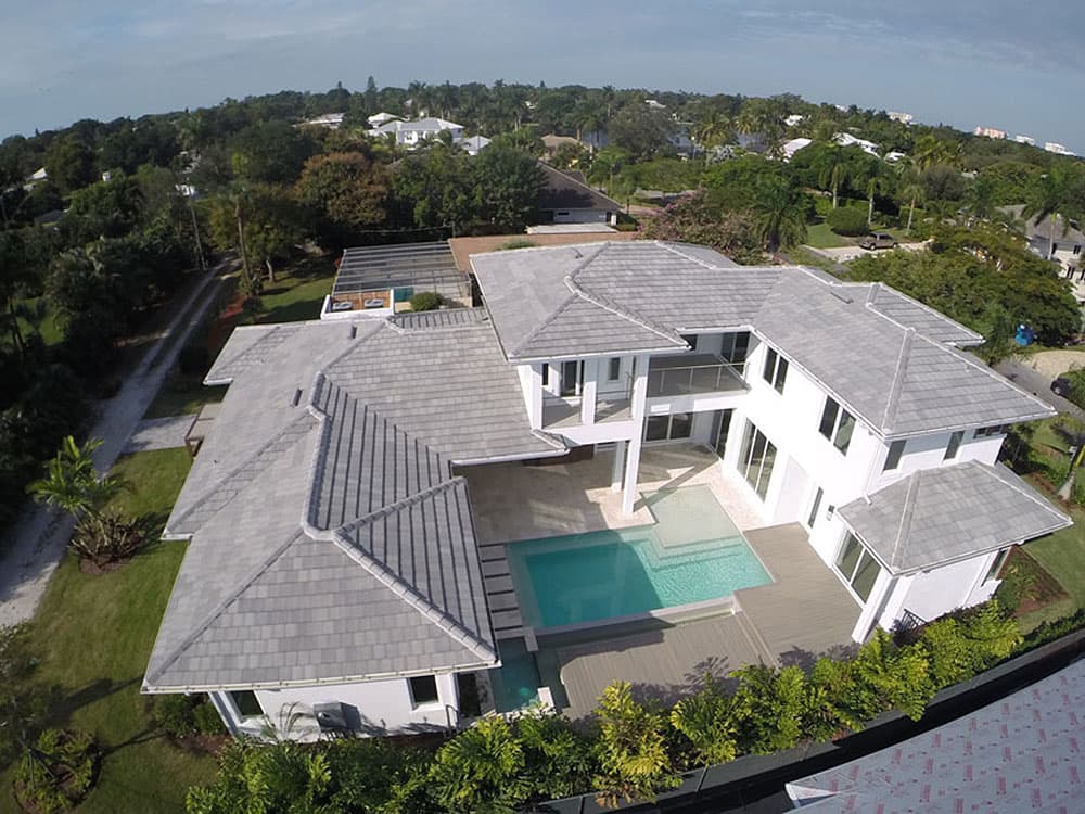 House plan exterior view of a modern two-story home with a U-shaped pool, multi-level rooflines, and a balcony.