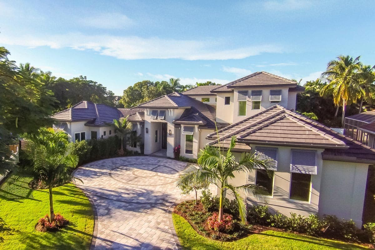 House plan exterior: Modern style, multi-story residence with a curved driveway, tile roof, and multiple gables.