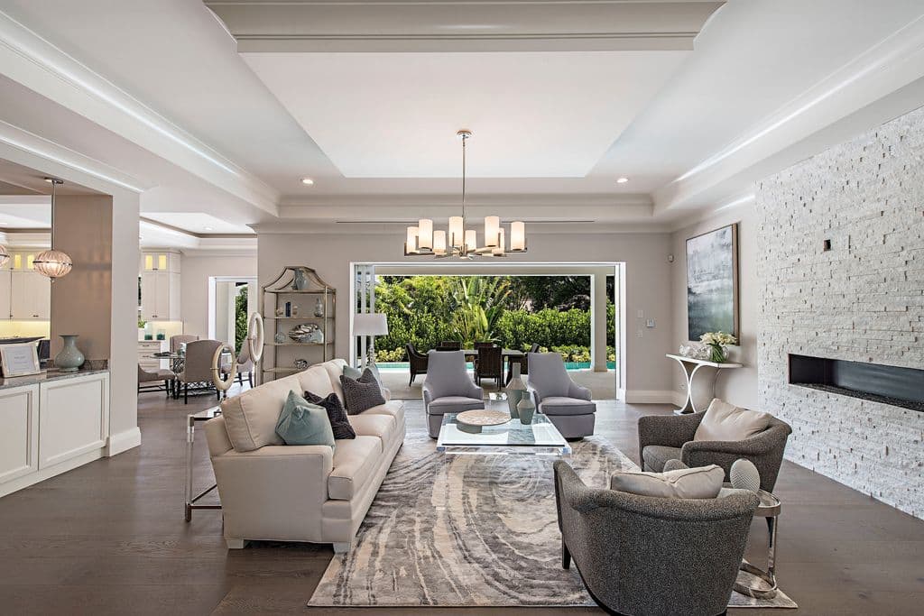 Great room interior with modern fireplace, tray ceilings, and large sliding glass doors opening to outdoor living space.