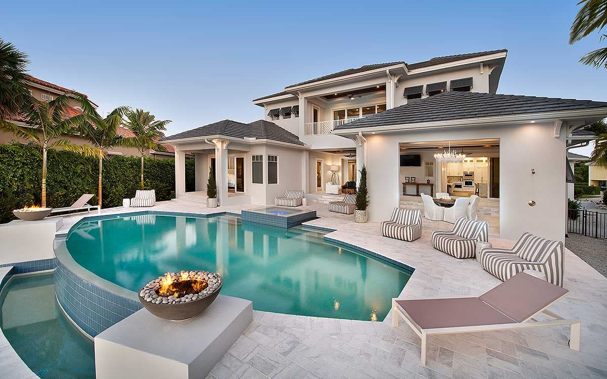 Modern house plan exterior with a two-story structure, curved pool, patio, and open-air dining area.