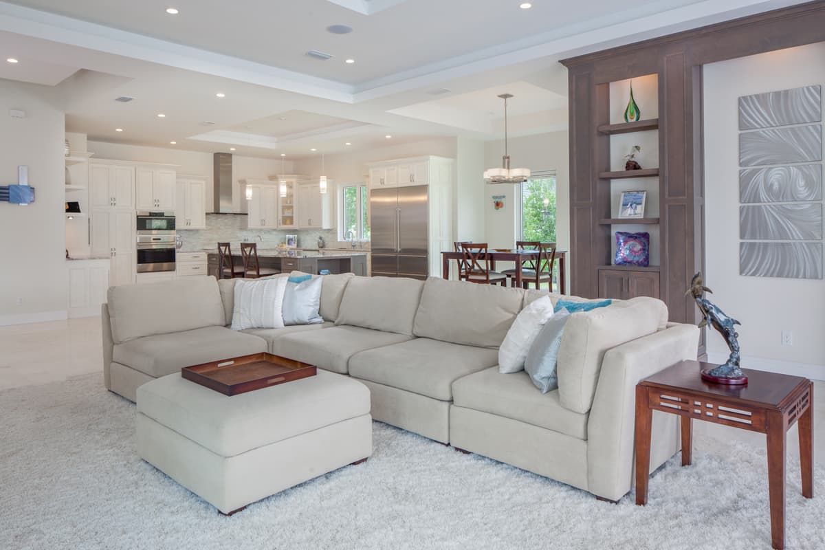 Open concept living area with sectional sofa, kitchen with island, dining area, and built-in shelving.