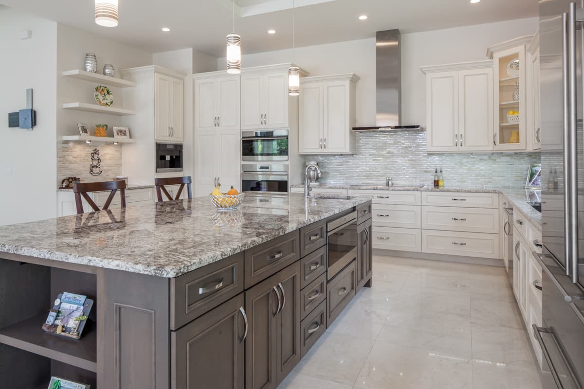 Contemporary kitchen with dark wood island, white shaker cabinets, stainless steel appliances, and mosaic tile backsplash.
