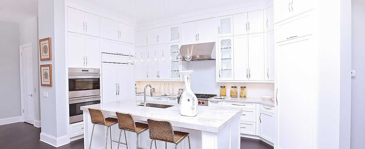 Contemporary kitchen with a large island, stainless steel appliances, white cabinets, and pendant lighting.