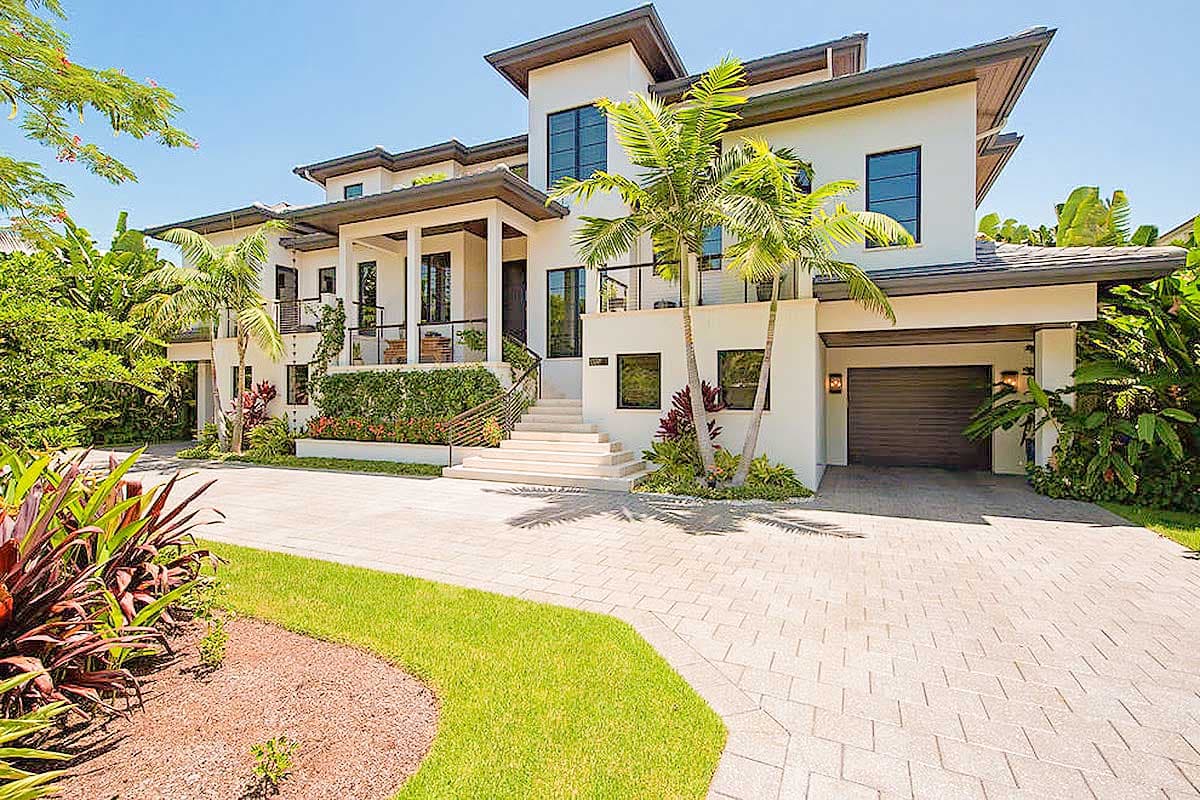 House plan exterior with modern design. Two-story home with porch, multi-gabled roof, and attached garage. Driveway with landscaping.