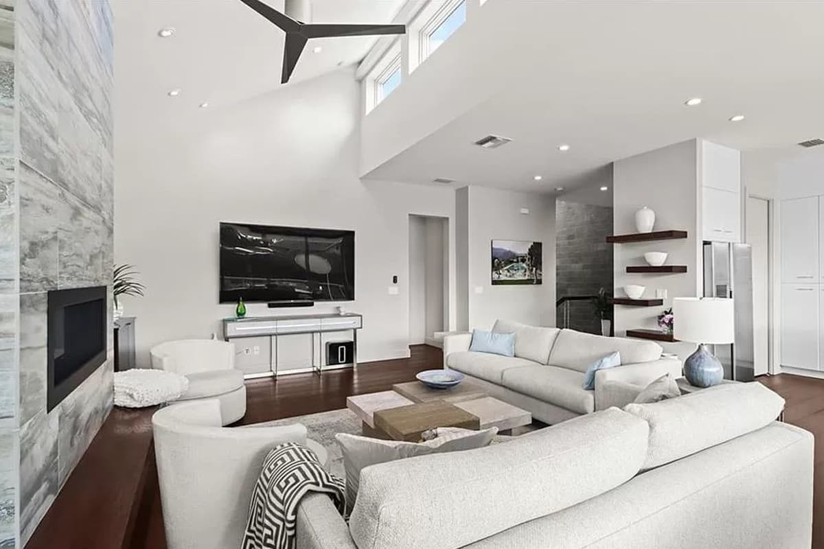 Interior view of a living room with vaulted ceiling, fireplace, sectional sofa, coffee table, and television.