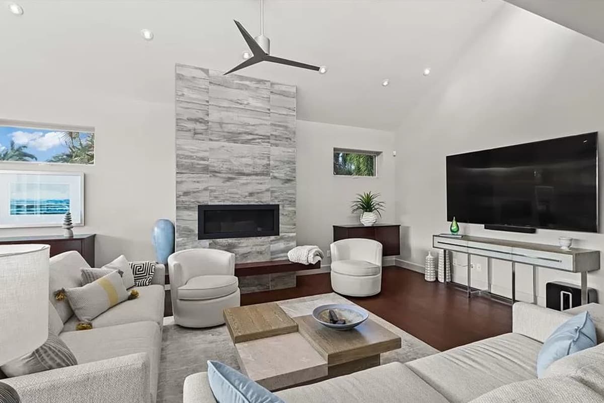 Interior view of a living room with vaulted ceiling, fireplace, and large television.