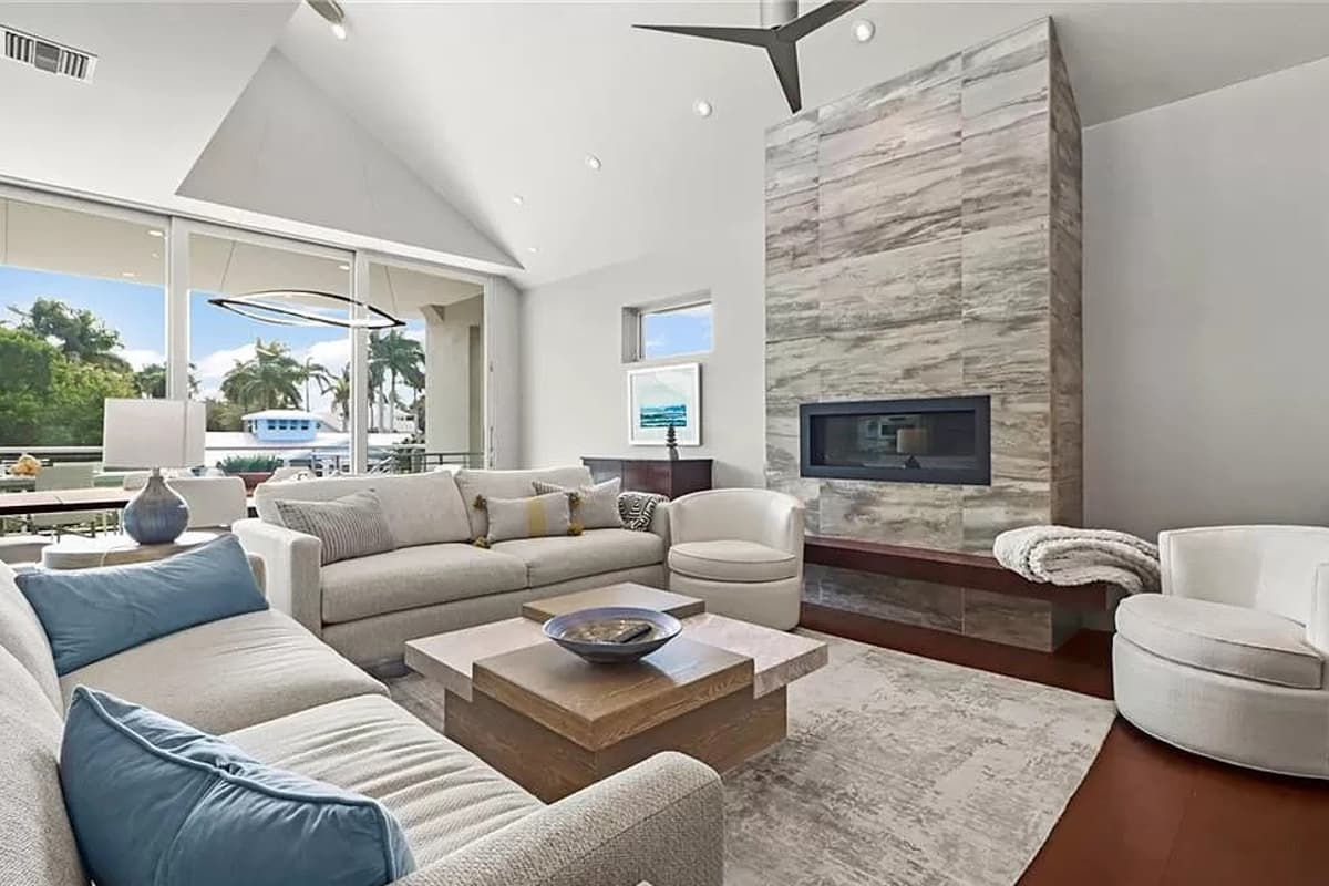 Living room with vaulted ceiling, linear fireplace, large windows, and sectional sofa.