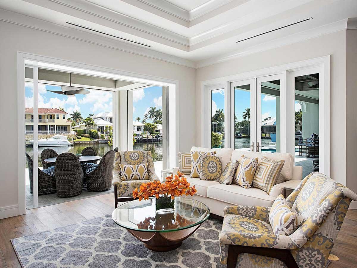 Great room with open layout, retractable glass doors leading to a canal view patio, coffered ceiling, and upholstered seating.