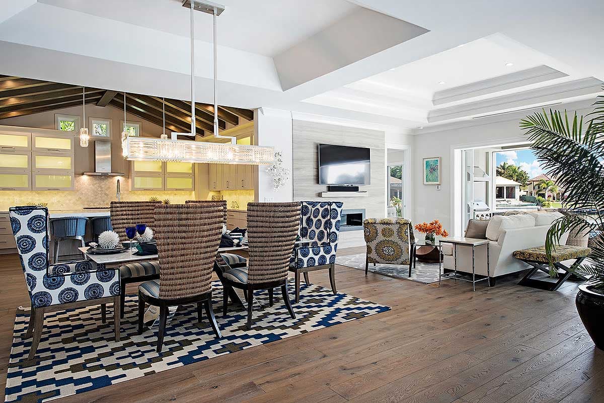 Open-concept living space with dining area, kitchen, and living room featuring a fireplace and large windows.