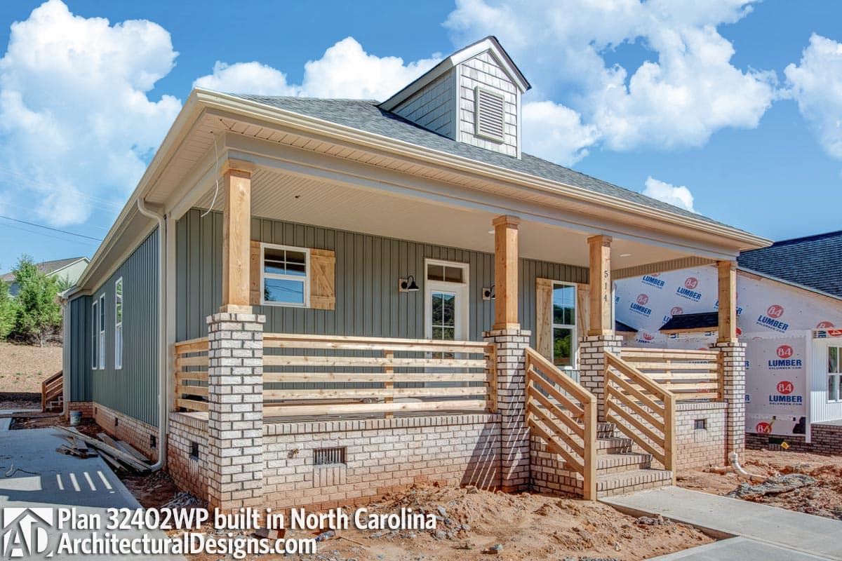 House plan exterior: One-story house with a covered front porch, wooden columns, brick foundation, and a dormer.