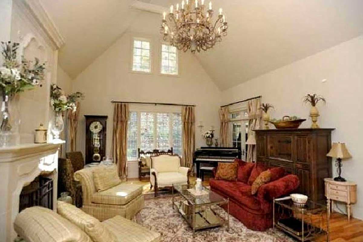 Living room with vaulted ceiling, fireplace, grand piano, and seating area.