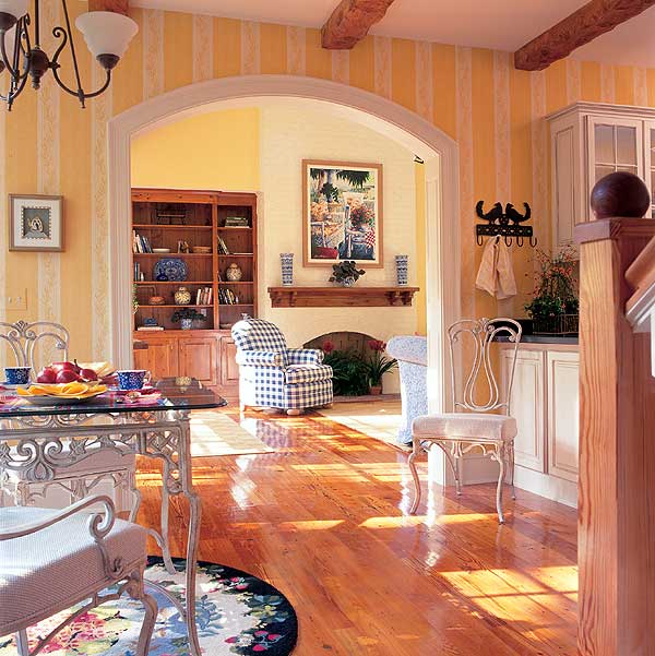 Interior view of a dining area and living room with fireplace, built-in bookshelves, and wood beam ceiling.